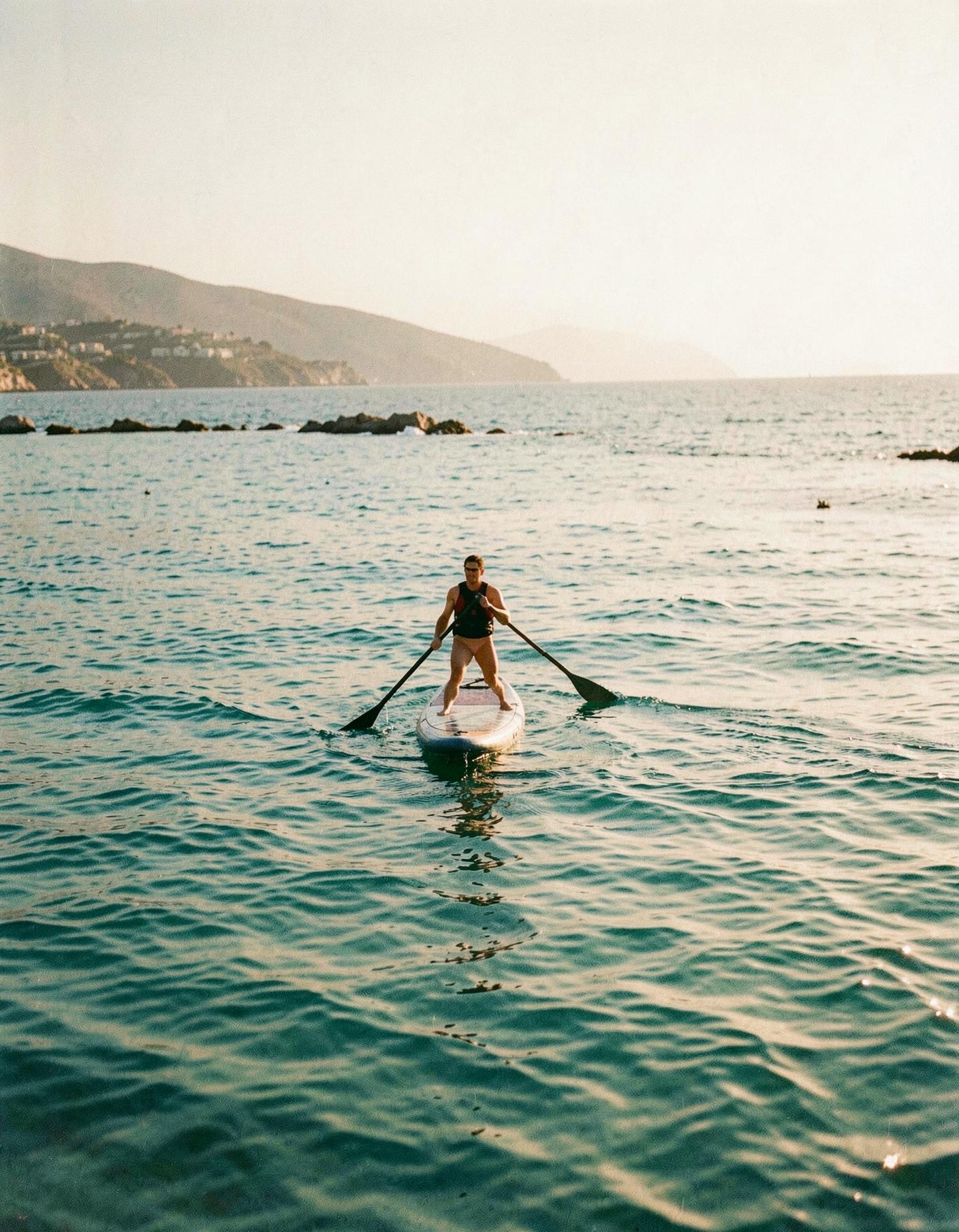 A paddleboarder on calm turquoise sea off the Limassol coast at golden hour